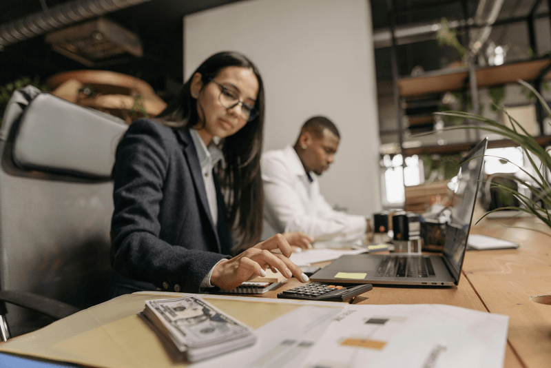 Woman on laptop with money on table